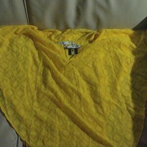 Yello see through shirt with gold clasp at throat.
